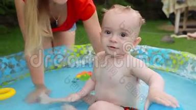 可爱的微笑宝宝在后院的充气游泳池玩耍